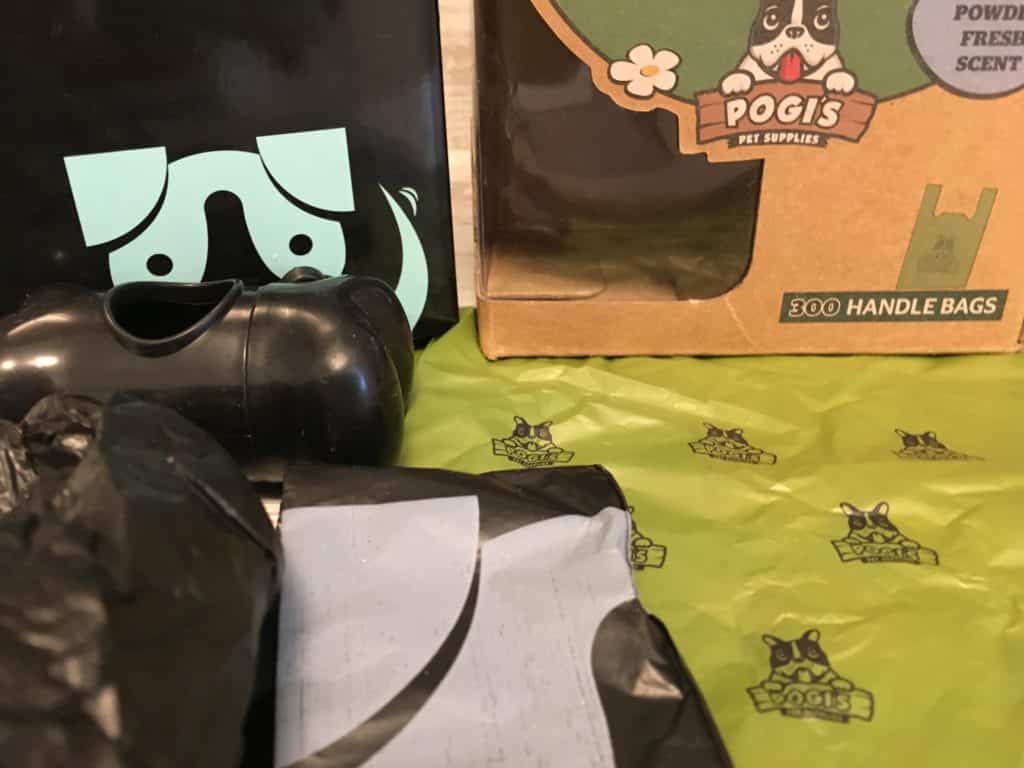 Hundekotbeutel in Schachteln und Rollen, inklusive praktischem Spender. Die Verpackung mit einer bezaubernden Hundeillustration und dem Markennamen Pogis Pet Supplies ist sehr empfehlenswert. Die Beutel sind elegant auf einem grün-schwarzen Untergrund präsentiert.